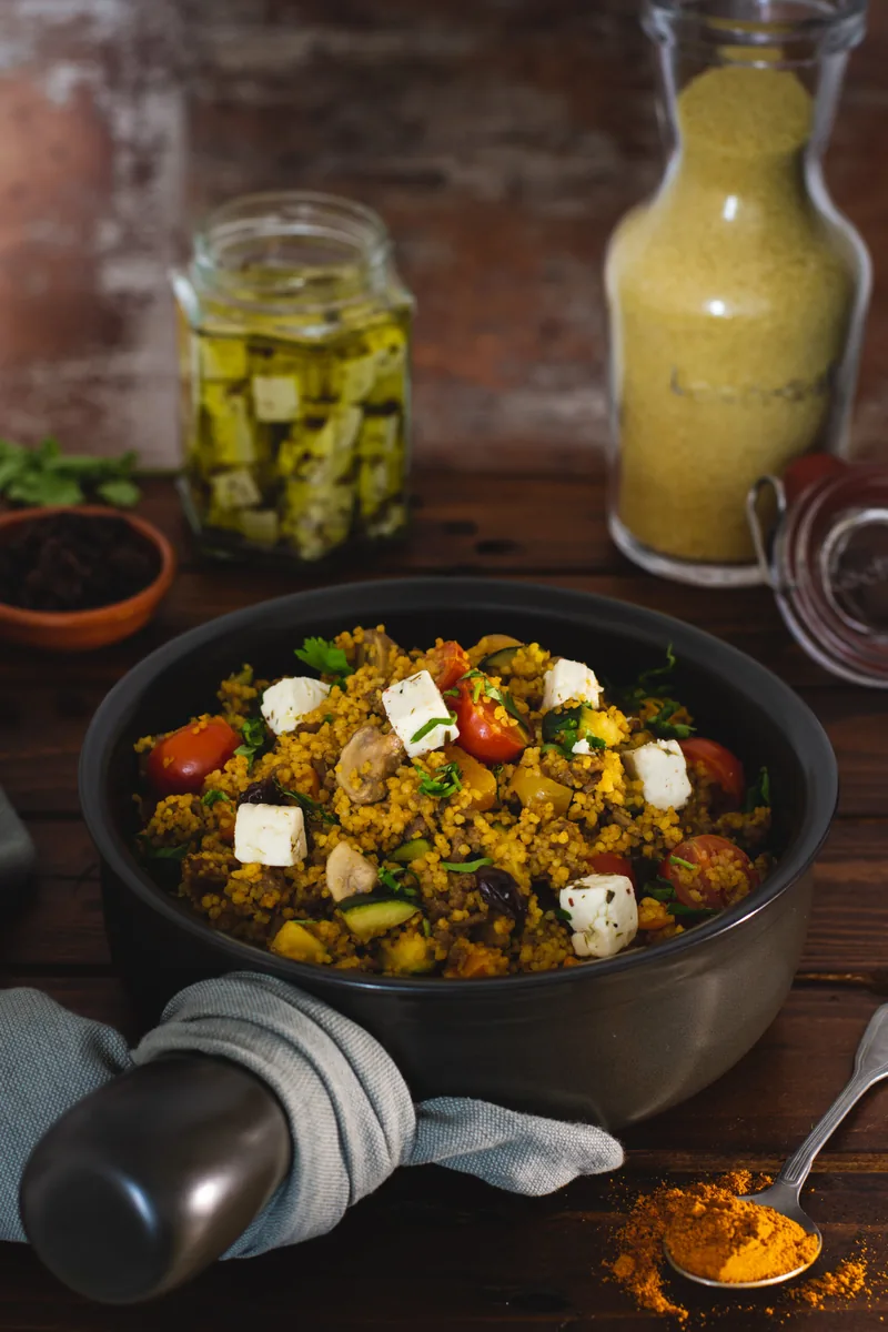 Een pan met groenterijst en feta, met flesjes ernaast
