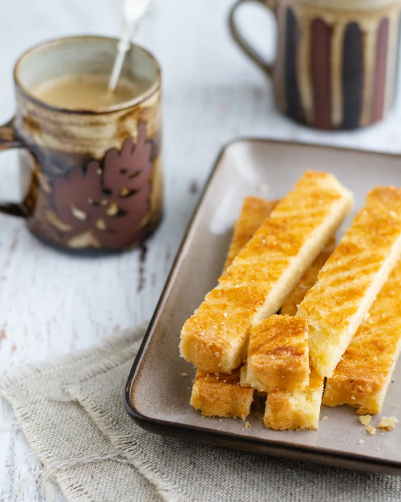 Bladerdeegstengels op een schaal met een kop koffie