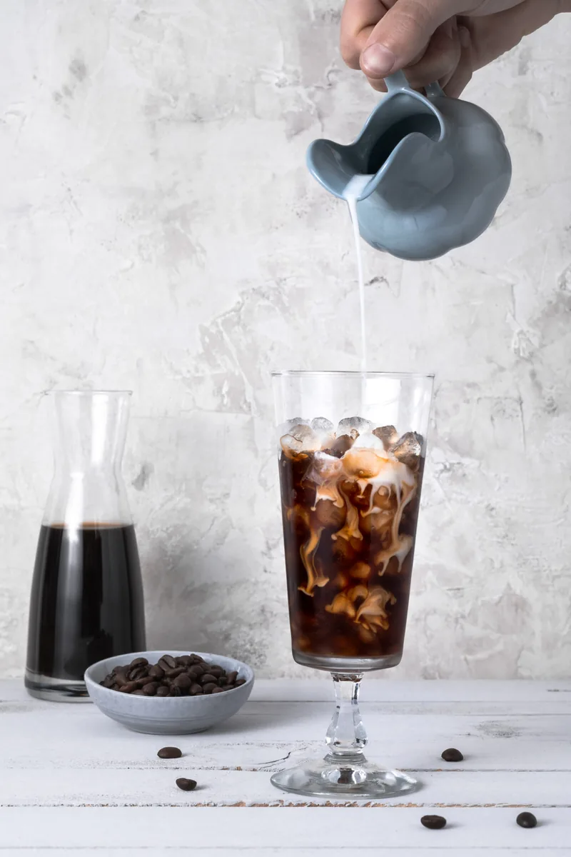 Koffie die in een glas met ijsblokjes wordt geschonken