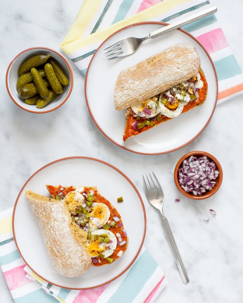 Twee borden met een gevulde wrap, augurkjes en rode ui