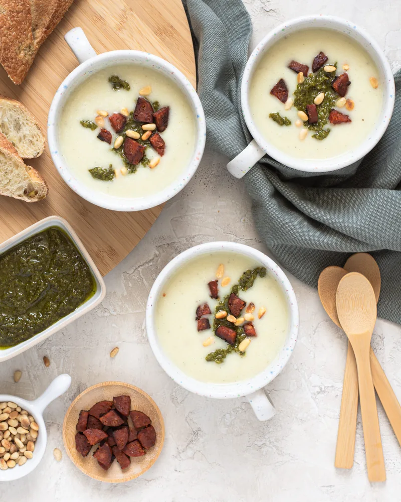 Drie kommen witte soep met spekjes, met pesto en brood erbij