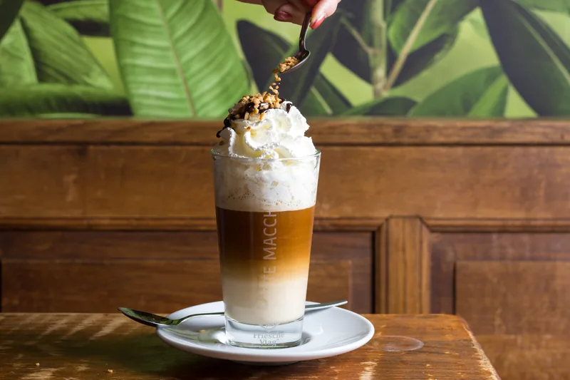 Een latte macchiato met slagroom waar saus overheen gaat