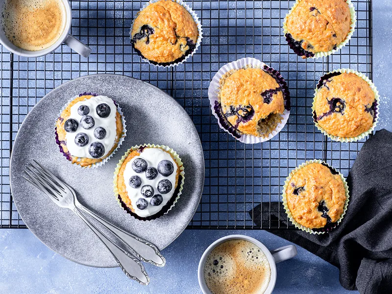 Ontbijtmuffins met blauwe bessen op een rooster, met twee koppen koffie
