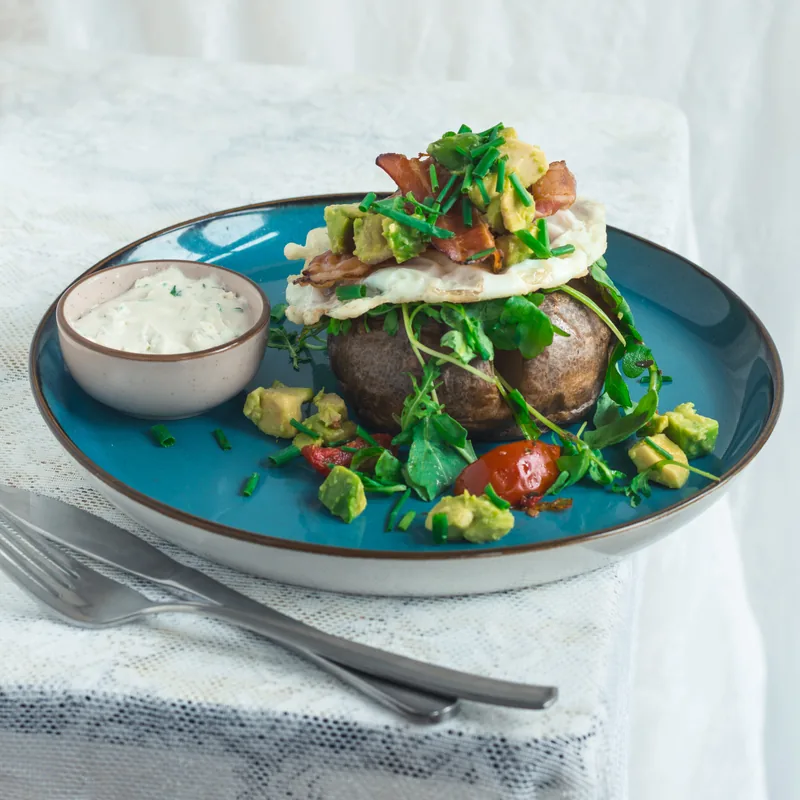 Een blauw bord met een gevulde aardappel en salade